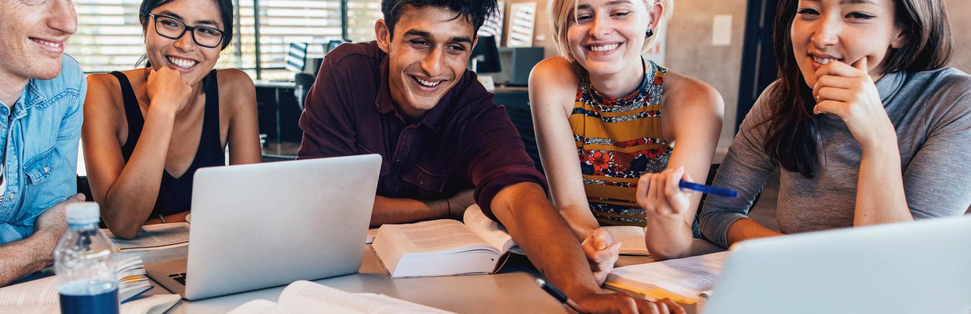 Des étudiants autour d'une table avec des livres et des ordinateurs
